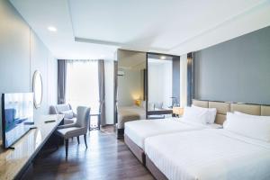 a hotel room with a large white bed and a chair at SureStay Plus by Best Western Sukhumvit 2 in Bangkok