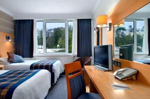 a hotel room with two beds and a desk with a television at Best Western Palace Hotel & Casino in Douglas