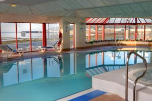 a large swimming pool with two chairs and windows at Best Western Palace Hotel & Casino in Douglas