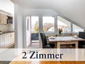 una cucina con tavolo e sedie e una grande finestra di Großzügige Ferienwohnung mit zwei Sonnenbalkonen in bester Bodenseelage l 1 Minute zum Bodensee l 2 Zimmer l Vollausgestattete Küche l Free-WLAN l Willkommen im Apartment Markelfingen a Radolfzell am Bodensee