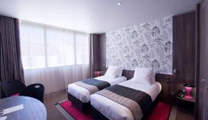 a hotel room with two beds and a window at Best Western Premier Le Patio des Artistes Wellness Jacuzzi in Cannes