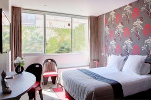 a hotel room with a bed and a table and a window at Best Western Premier Le Patio des Artistes Wellness Jacuzzi in Cannes