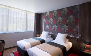 two beds in a hotel room with a wallpaper at Best Western Premier Le Patio des Artistes Wellness Jacuzzi in Cannes