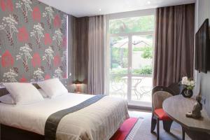 a bedroom with a bed and a table and a window at Best Western Premier Le Patio des Artistes Wellness Jacuzzi in Cannes