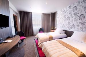 a hotel room with two beds and a flat screen tv at Best Western Premier Le Patio des Artistes Wellness Jacuzzi in Cannes