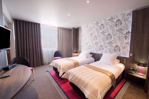 a hotel room with two beds and a television at Best Western Premier Le Patio des Artistes Wellness Jacuzzi in Cannes