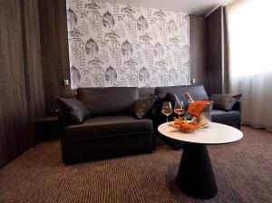 a living room with a couch and a table with wine glasses at Best Western Premier Le Patio des Artistes Wellness Jacuzzi in Cannes