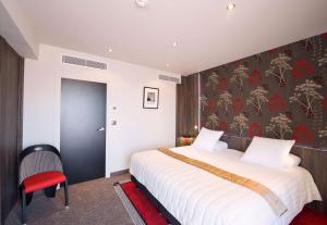 a bedroom with a large bed and a red chair at Best Western Premier Le Patio des Artistes Wellness Jacuzzi in Cannes