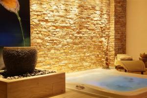 a bath tub in a room with a stone wall at Best Western Premier Le Patio des Artistes Wellness Jacuzzi in Cannes