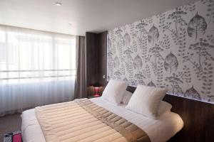 a bedroom with a white bed with a floral wallpaper at Best Western Premier Le Patio des Artistes Wellness Jacuzzi in Cannes