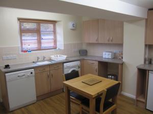 a kitchen with a table and a sink and a stove at Cottage on the Green in Brackley