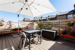 a table and chairs on a balcony with an umbrella at Veeve - Rubix Cube Mews in London