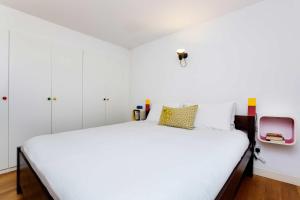 a bedroom with a white bed and white cabinets at Veeve - Rubix Cube Mews in London