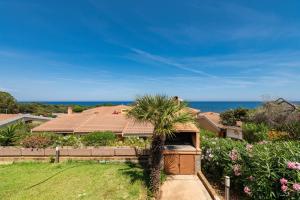 a house with a palm tree in a yard at Villetta Residence Porto Corallo in Villaputzu