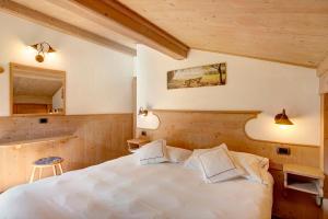 Un dormitorio con una cama blanca y un espejo. en Appartamento Castagno Chalet Cambra, en Livigno