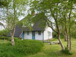 une maison bleue et blanche avec des arbres devant elle dans l'établissement Ferienwohnung "Emil", à Sankt Peter-Ording