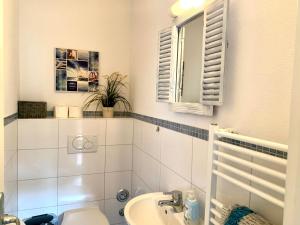 a bathroom with a sink and a toilet and a mirror at Ferienwohnung "DECK 1" in Sankt Peter-Ording