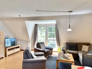 a living room with a couch and chairs and a tv at Zum Leuchtturm - Ferienwohnung 3 in Sankt Peter-Ording