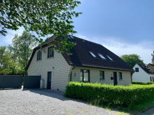 a small white house with a black roof at Ferienwohnung 3 in der Waldstraße in Sankt Peter-Ording