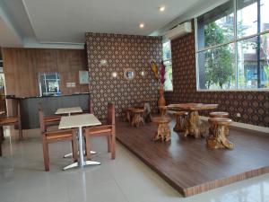 a restaurant with wooden tables and wooden chairs at Golden Ganesha Hotel Yogyakarta by Ecommerceloka in Gondowulung