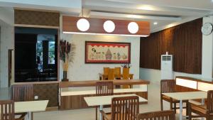 a restaurant with tables and chairs and a counter at Golden Ganesha Hotel Yogyakarta by Ecommerceloka in Gondowulung +18 photos