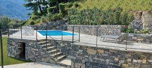 uma parede de pedra com uma escada ao lado de uma piscina em Villa Ortensia em Laglio