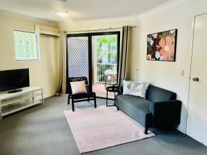 Una sala de estar con un sofá y un televisor. en Spring Hill Gardens Apartments, en Brisbane