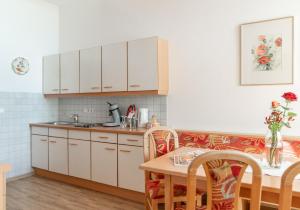 uma cozinha com armários brancos e uma mesa com cadeiras em Familienhotel Unterreith em Forstau