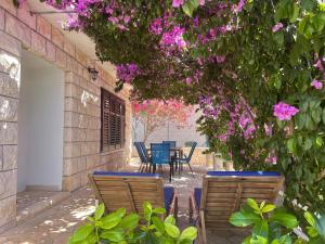 Un patio con sillas y una mesa con flores rosas. en Vacation house Benedetto, en Supetar
