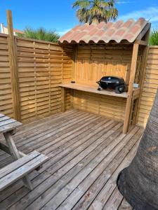 a wooden deck with a wooden pergola with a radio at La perle rare in Le Grau-dʼAgde