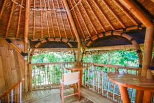 une chambre avec deux tables et une chaise sur un balcon dans l'établissement Le Bamboo Bali, à Uluwatu