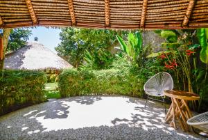 a patio with a table and chairs in a garden at Le Bamboo Bali in Uluwatu