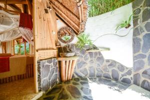 a house with a stone wall and a patio at Le Bamboo Bali in Uluwatu