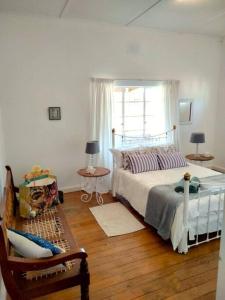 a bedroom with a bed and a chair and a window at Sunnyside Farm Cottage, Oudtshoorn, South Africa in Oudtshoorn