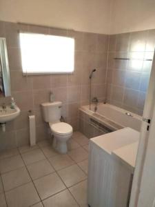 a bathroom with a toilet and a tub and a sink at Sunnyside Farm Cottage, Oudtshoorn, South Africa in Oudtshoorn