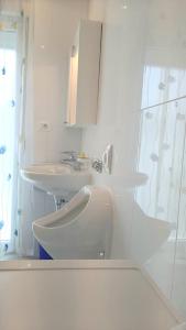 La salle de bains blanche est pourvue d'un lavabo et de toilettes. dans l'établissement Doppelzimmer mit Bad, Terrasse und Pool, à Ližnjan