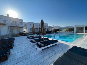 a row of lounge chairs next to a swimming pool at Margie Mykonos Hotel in Mikonos