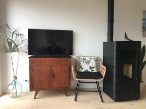 a living room with a chair and a television on a wooden cabinet at Maison de Vacances 2 personnes, ossature bois, à Saint Gilles Croix De Vie 85 in Saint-Gilles-Croix-de-Vie