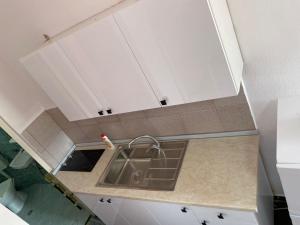 uma cozinha com um lavatório e armários brancos em Willy Apartments em Velipojë