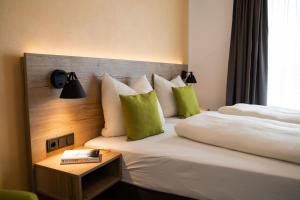 a hotel room with two beds with green pillows at Albhotel Bahnhöfle in Stubersheim