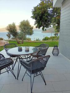 een tafel en stoelen op een patio met uitzicht op de oceaan bij Nerea in Ayia Evfimia