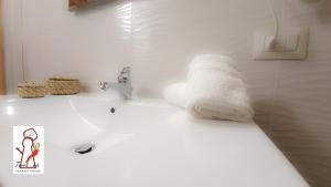 La salle de bains blanche est pourvue d'un lavabo et d'une serviette. dans l'établissement Terramia Holiday House, à Naples