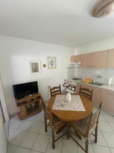 a kitchen with a table and chairs and a television at Apartments Pecotić in Brna