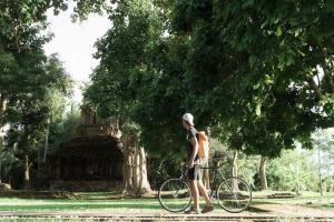SukSanti CoLiving and Vacation في شيانج راي: رجل واقف بالدراجة في الحديقة