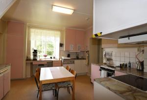 cocina con armarios rosas, mesa y sillas en Cozy holiday home located on Gotland en Slite