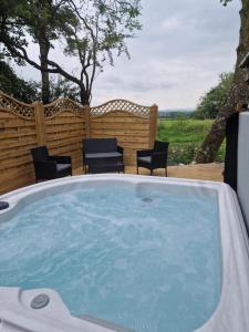 a jacuzzi tub in a yard with chairs at Squirrel Cottage in Ballymena
