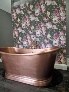 a copper tub in a bathroom with a floral wallpaper at Squirrel Cottage in Ballymena
