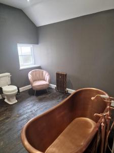 a bathroom with a wooden tub and a pink chair at Squirrel Cottage in Ballymena