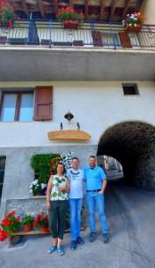Capovalle的住宿－LA CA' DEI COMARI - Locanda da Tullio，站在一座建筑前面的三人小组