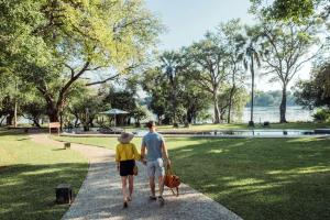 a man and a woman walking through a park at Palm River Hotel in Victoria Falls